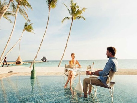 Couple dining beside a tropical resort pool